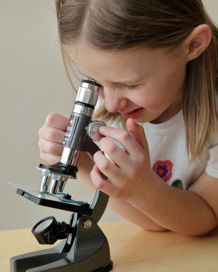 A young girl looks into a microscope