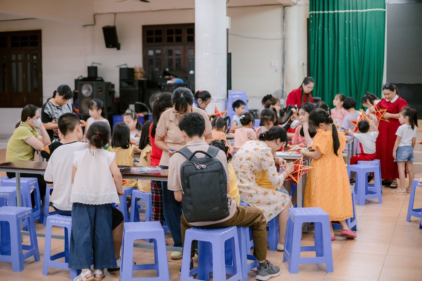 A cafeteria full of children and parents working at long tables during a school event