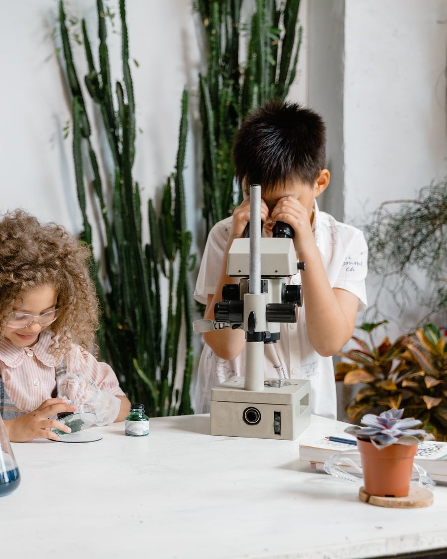 A boy looks through a microscope at a classroom table